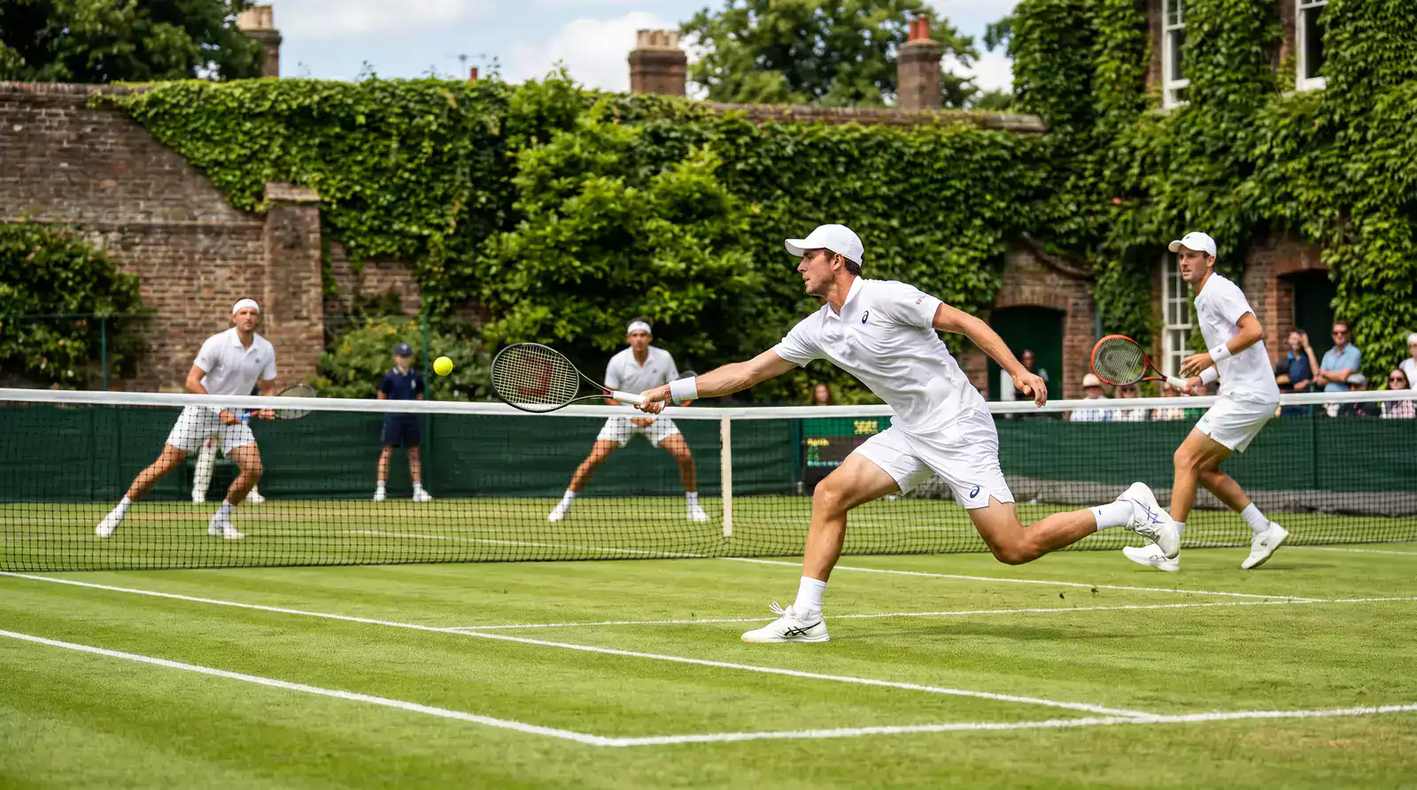 Doubles tennis players on grass court at Wimbledon preparing to serve during a match